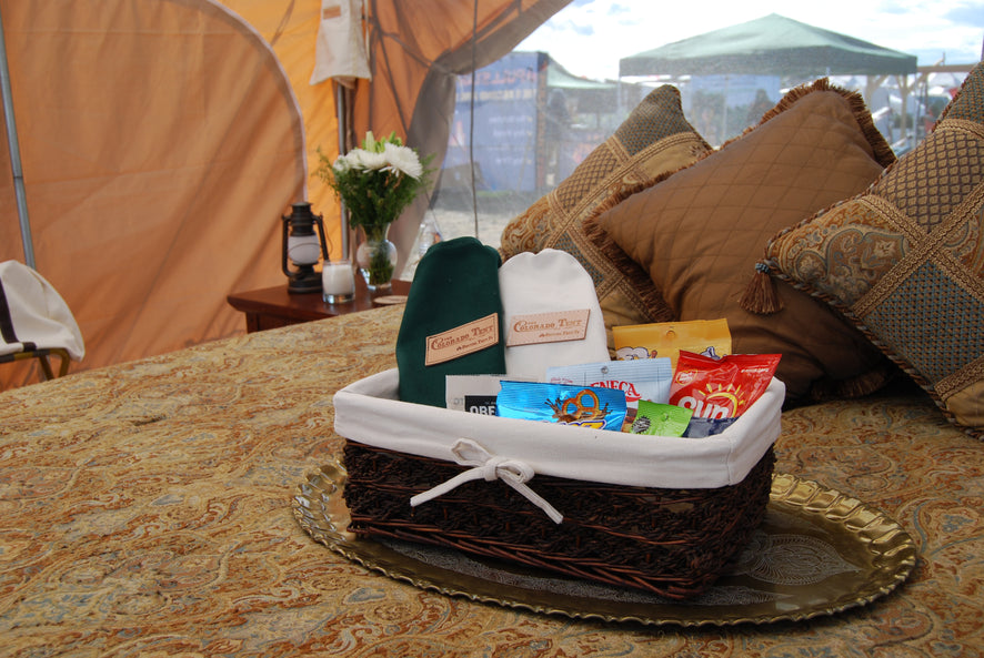 Green and natural canvas drawstring bags with Colorado Tent labels in a gift basket inside a tent.