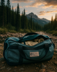Evergreen Cordura Colorado Tent duffel bag with black straps placed on forest trail