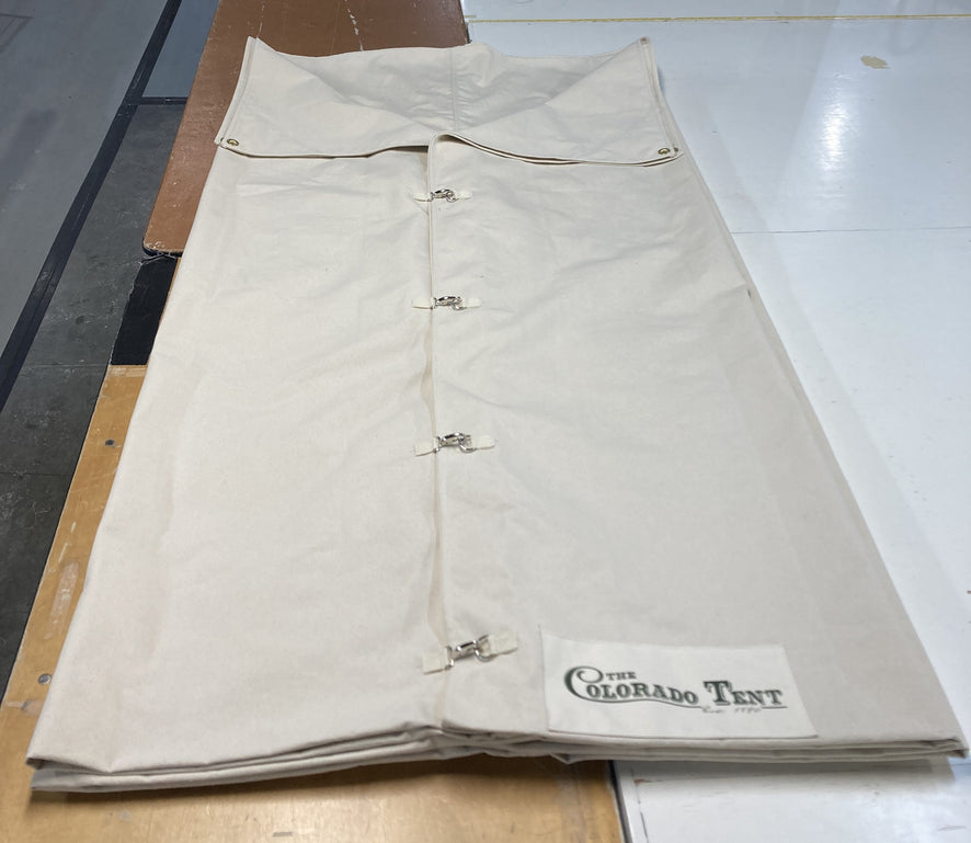 Natural canvas bedroll folded flat on a shop table, with snap closures and a Colorado Tent label.