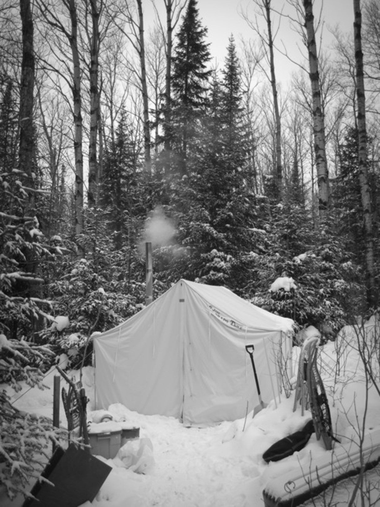 Canvas wall tent pitched in snow with stove pipe