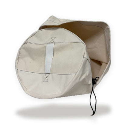 Natural canvas Coupler Bag on its side, showing the end handle and drawstring, on a white background
