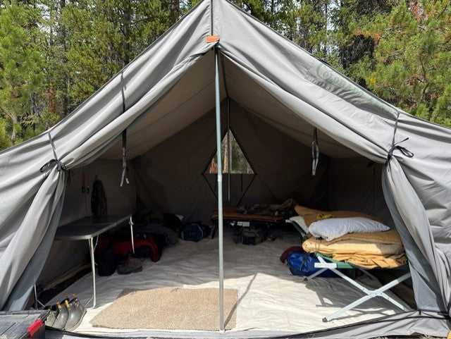 Inside the 1890 in WeatherMax 80 at elk camp: cots, a camp table, and the rear window