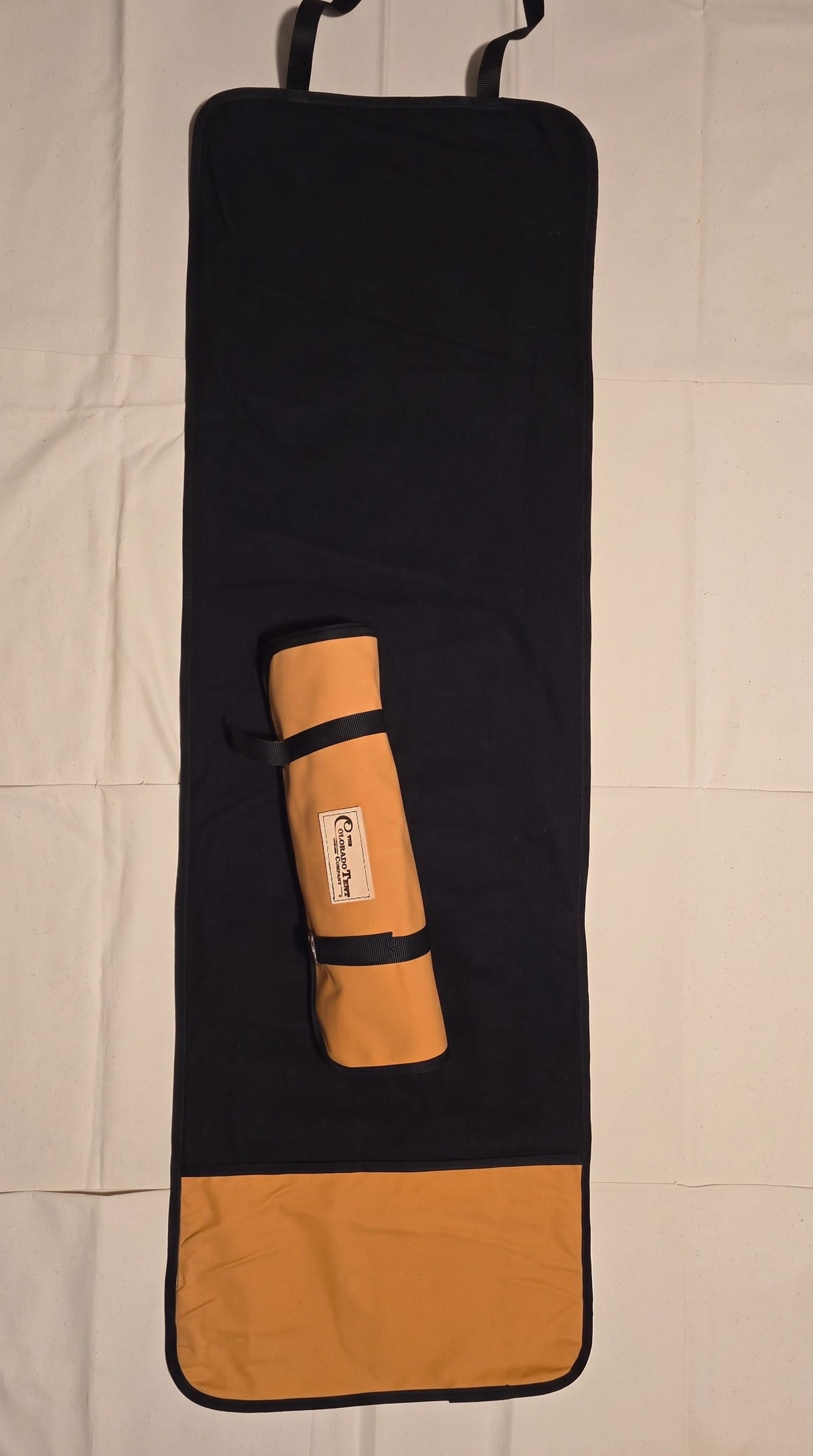 Gun Cleaning Mat in black felt with a tan canvas pocket panel, hanging straps, and the matching rolled tool pouch