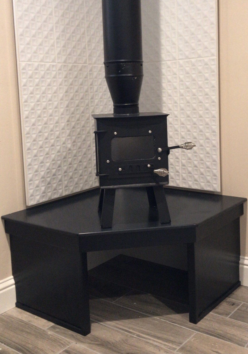 Mini Woodsman Wood Stove by North Woods Fabrication, installed on a hearth with stove pipe