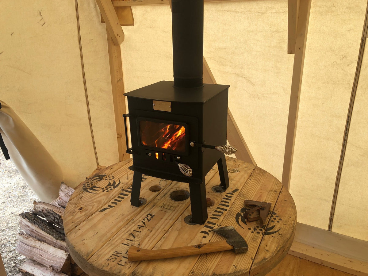 Mini Woodsman Wood Stove by North Woods Fabrication, burning in a canvas wall tent
