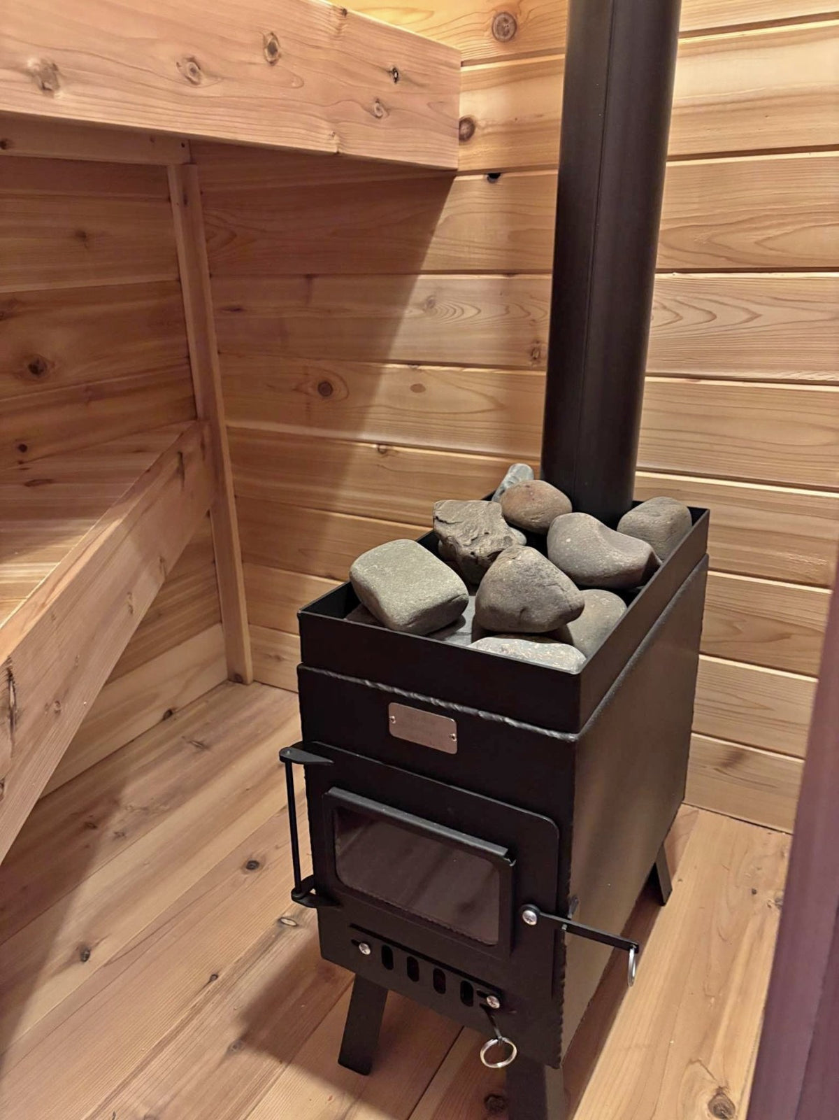 Sauna Wood Stove Kit by North Woods Fabrication, with sauna rocks in a cedar sauna