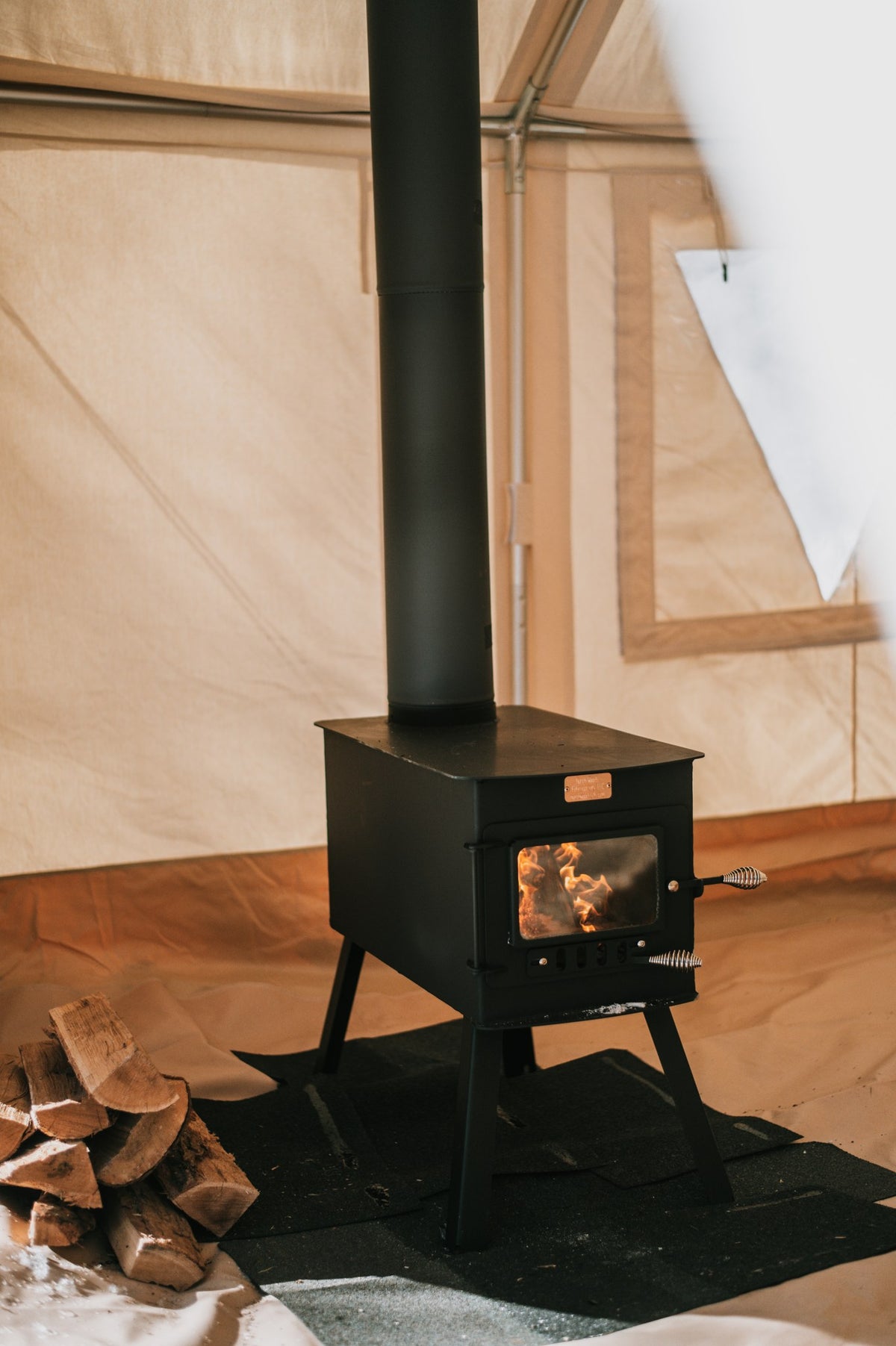 Woodsman XL Wood Stove by North Woods Fabrication, burning in a canvas tent