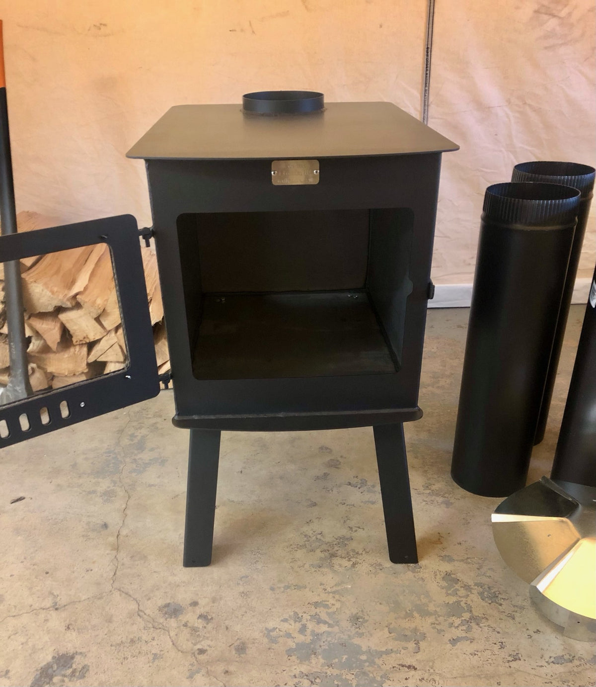 Woodsman XXL Stove Kit by North Woods Fabrication, door open, stove pipe beside it