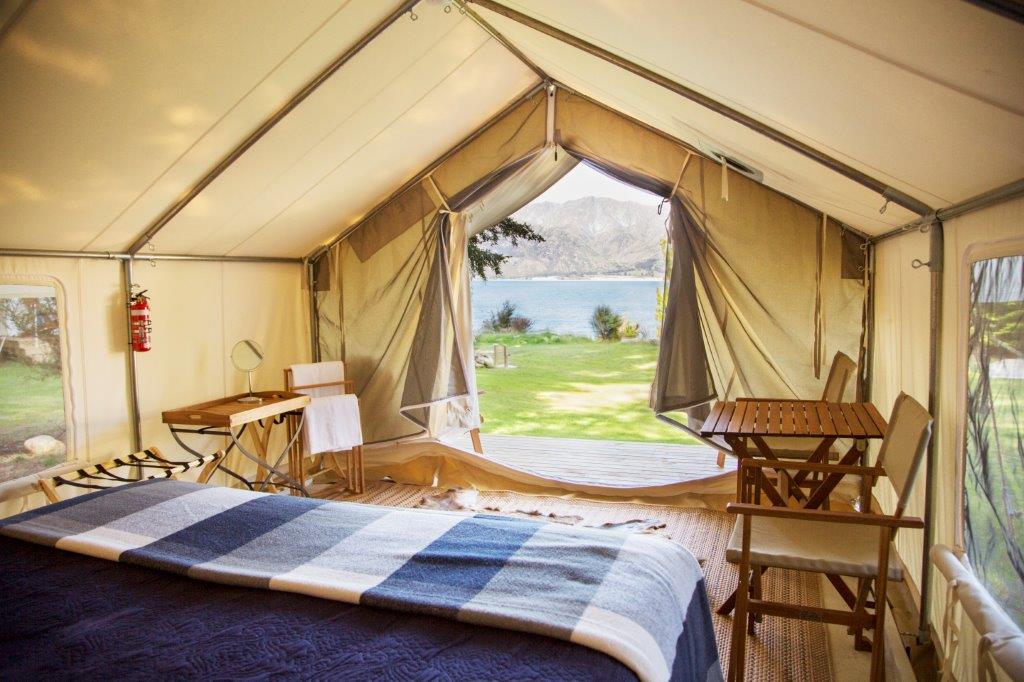 Interior of Colorado wall tent showing mountain lake view through open door