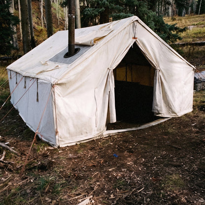 The 1890 canvas wall tent with a stove pipe through the roof jack, in a pine forest