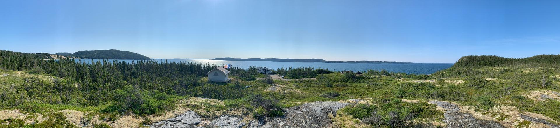 Canvas wall tent overlooking ocean and forested cliffs in Newfoundland, Canada
